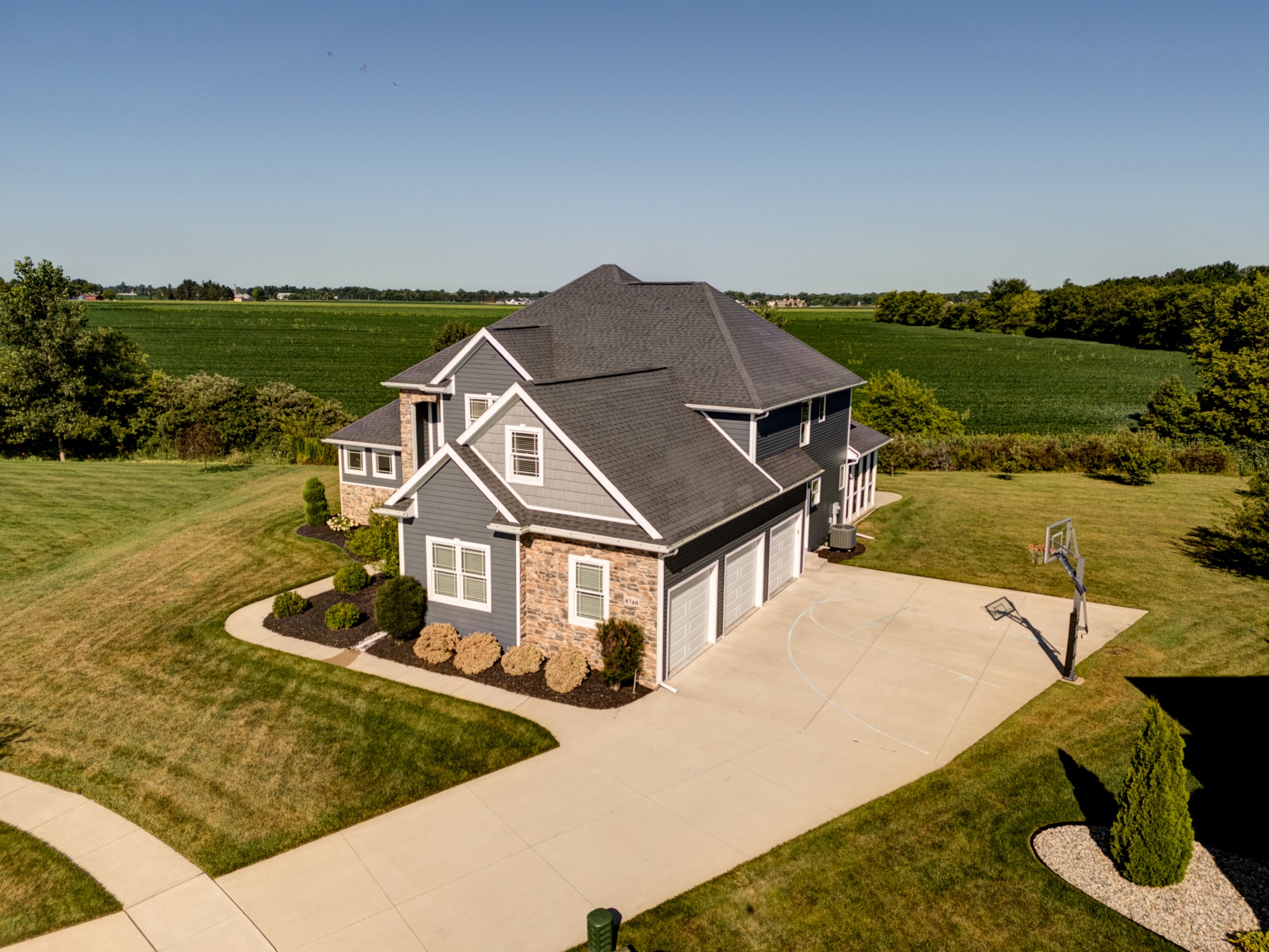 Aerial view of the home, three-car garage, driveway and open surroundings