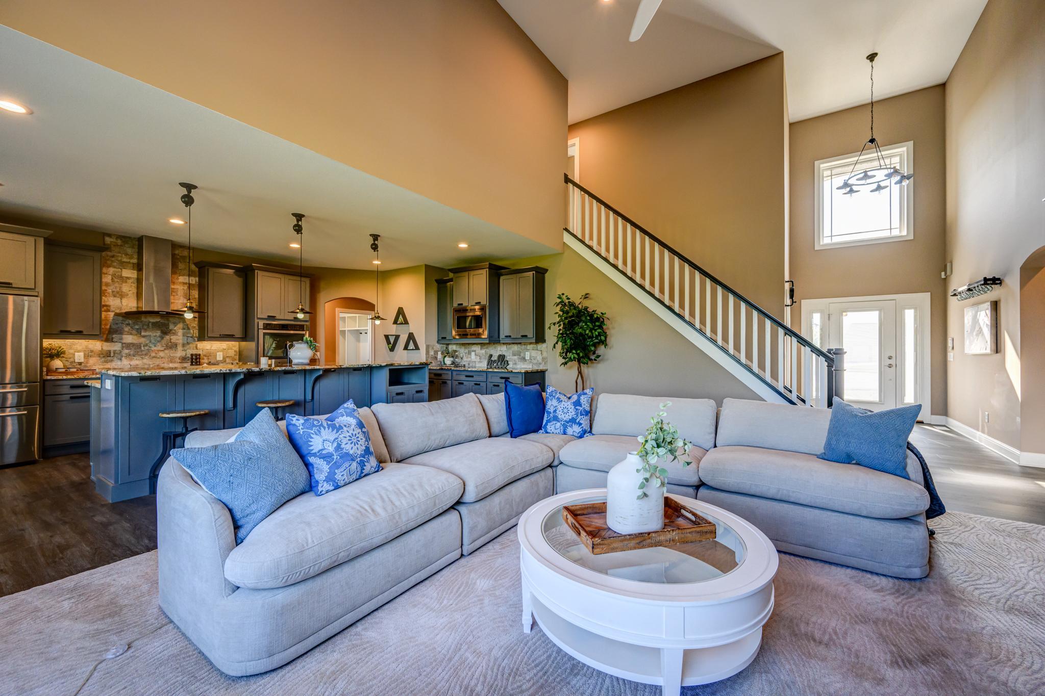 Open living room and kitchen with vaulted ceiling and staircase